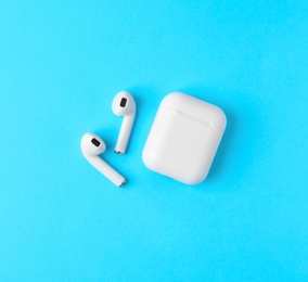 Photo of Modern wireless earphones and charging case on light blue background, flat lay. Space for text