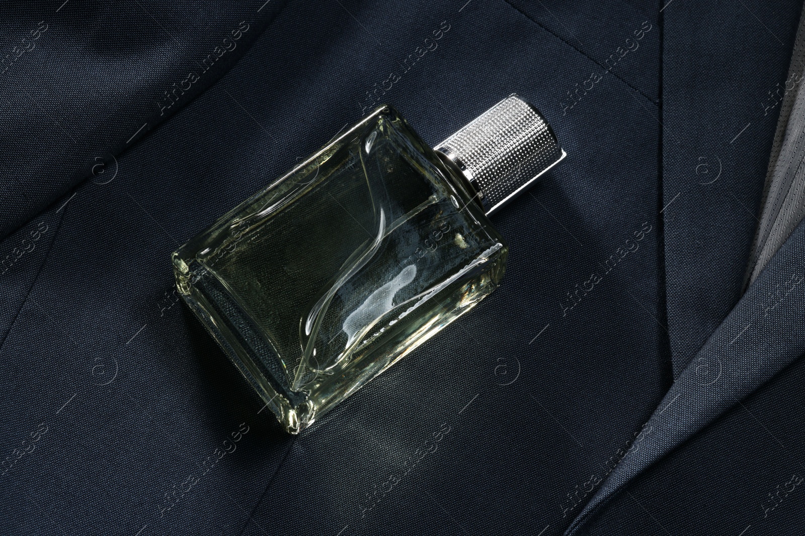 Photo of Luxury men's perfume in bottle on grey jacket, above view