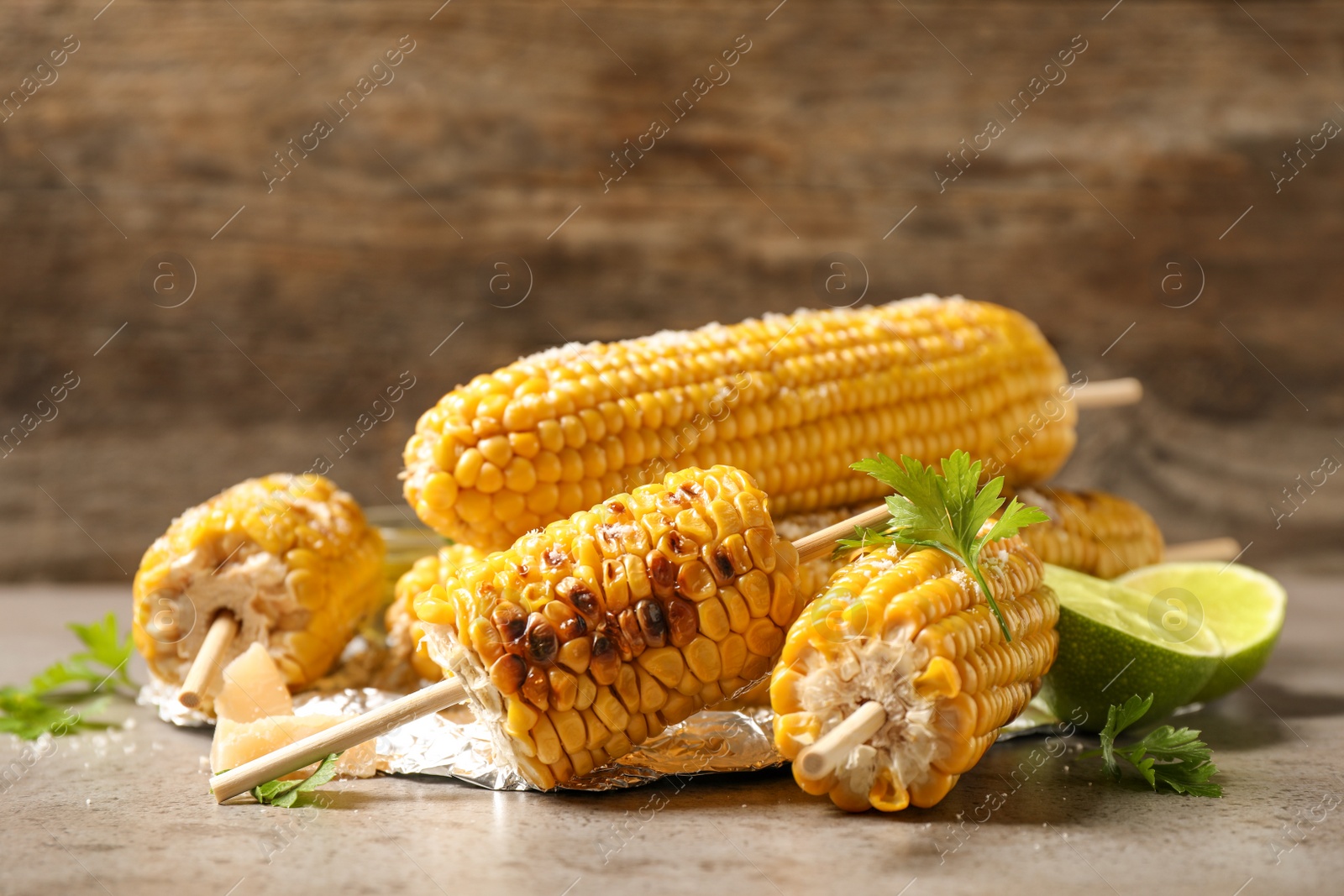 Photo of Delicious grilled corn cobs on grey table