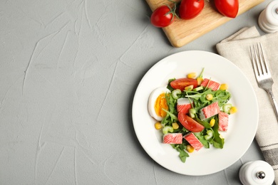 Delicious crab stick salad served on grey table, flat lay. Space for text