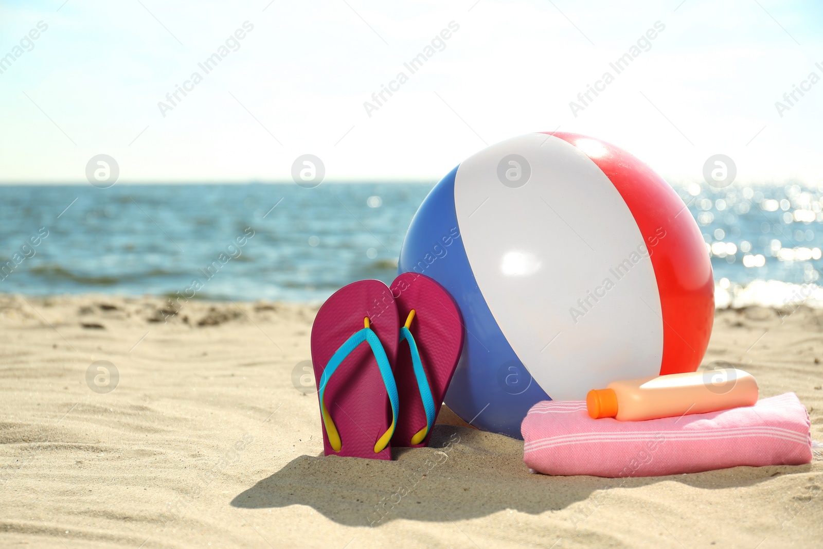 Photo of Inflatable ball and beach objects on sand near sea, space for text