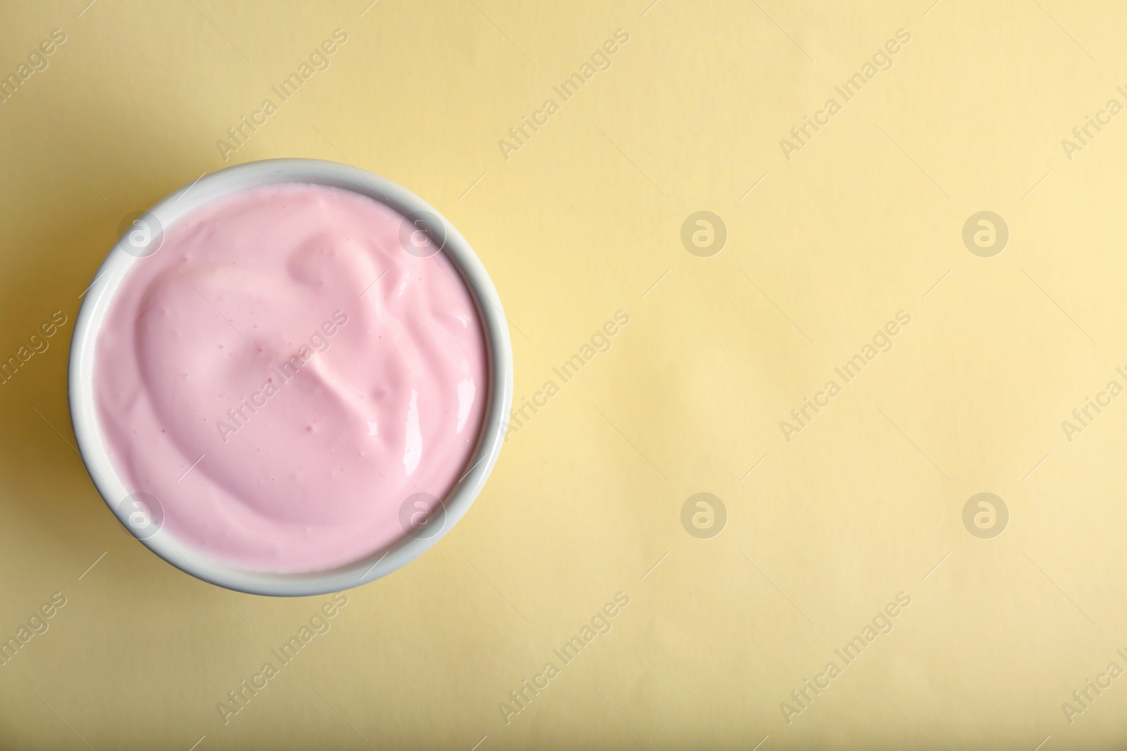 Photo of Bowl with tasty yogurt on color background, top view