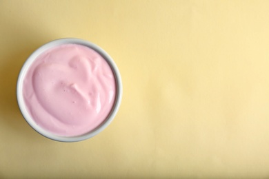 Photo of Bowl with tasty yogurt on color background, top view