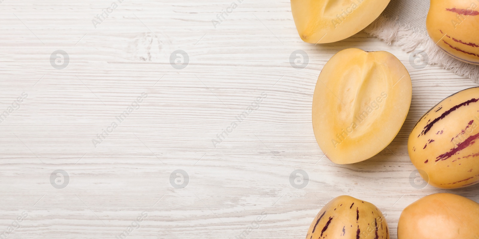 Image of Fresh ripe pepino melons on white wooden table, flat lay with space for text. Banner design
