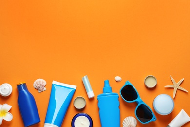 Photo of Flat lay composition with sun protection cosmetic products on orange background, space for text