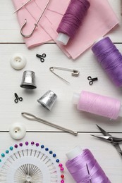 Flat lay composition with thimbles and different sewing tools on white wooden table
