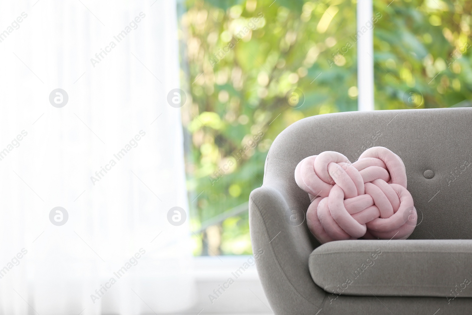 Photo of Unusual pillow on sofa against window in room interior