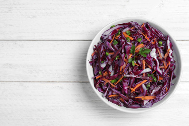 Photo of Fresh red cabbage salad on white wooden table, top view. Space for text