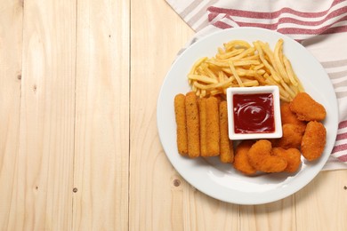 Plate with tasty ketchup, fries, chicken nuggets and cheese sticks on wooden table, top view. Space for text