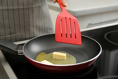 Photo of Woman stirring melted butter in frying pan on stove, closeup