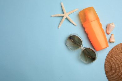 Flat lay composition with bottle of sunscreen on light blue background. Space for text