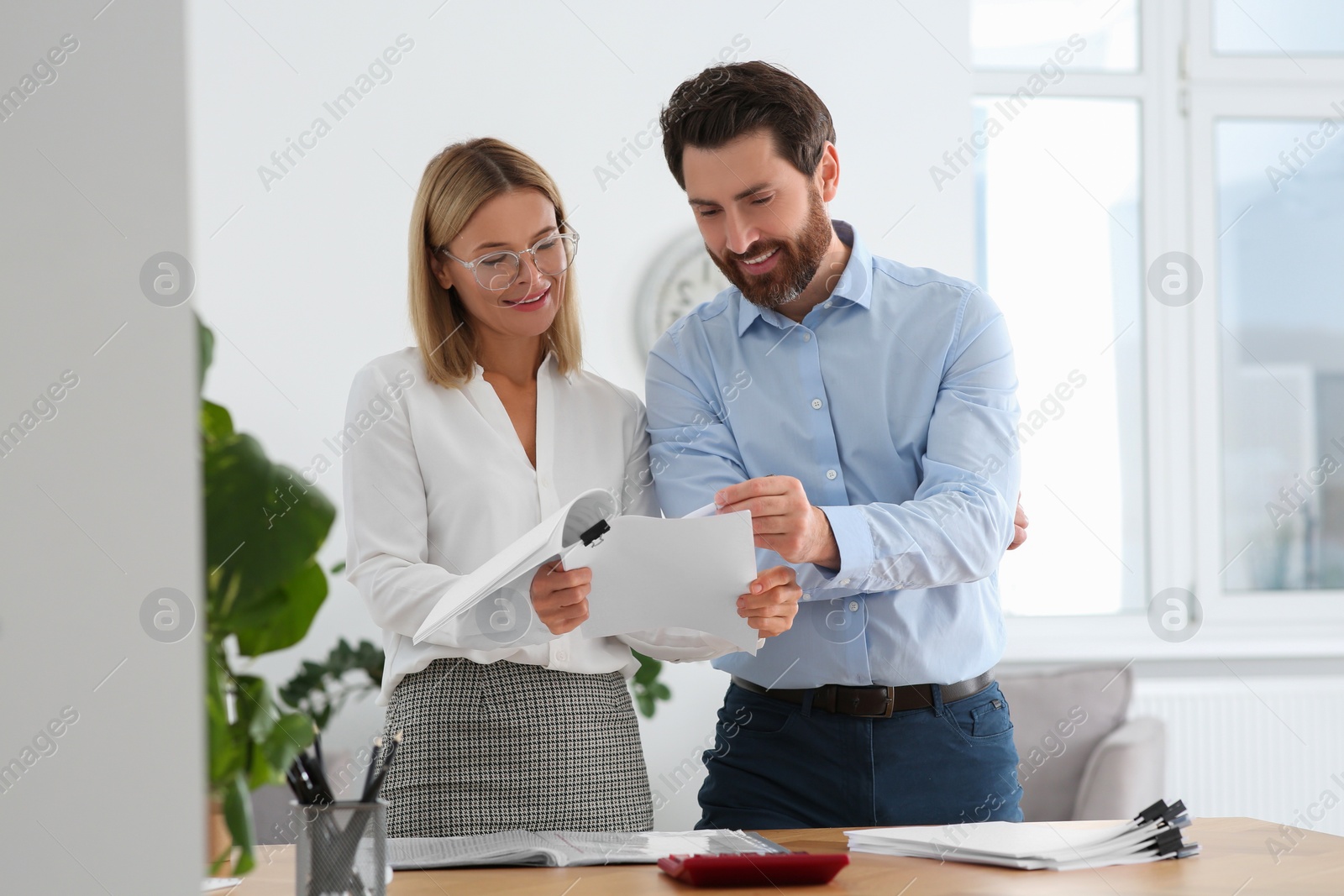 Photo of Happy businesspeople working with documents in office