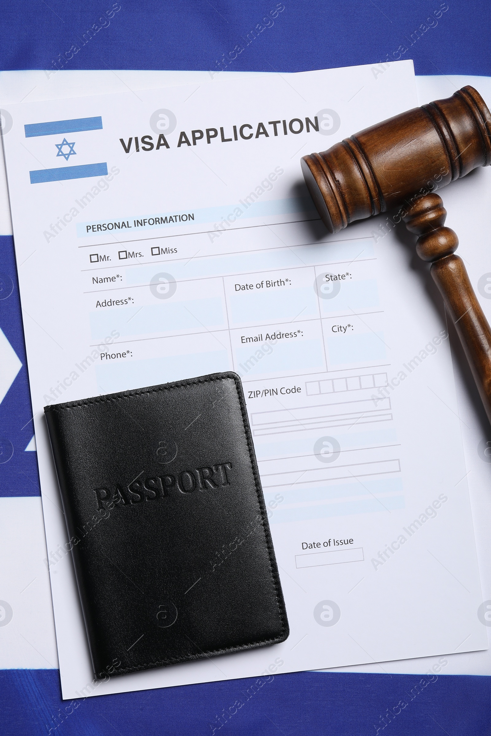 Photo of Immigration to Israel. Visa application form, gavel and passport on flag, flat lay