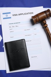 Immigration to Israel. Visa application form, gavel and passport on flag, flat lay