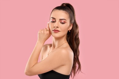 Beautiful woman with elegant jewelry on pink background