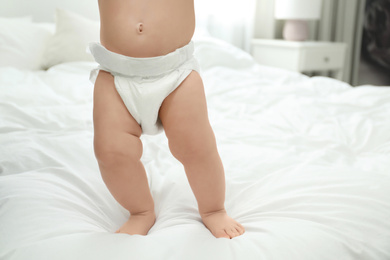 Photo of Cute little baby in diaper on bed, closeup. Space for text