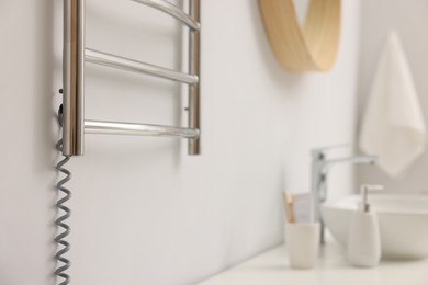 Photo of Heated towel rail on white wall in bathroom, closeup