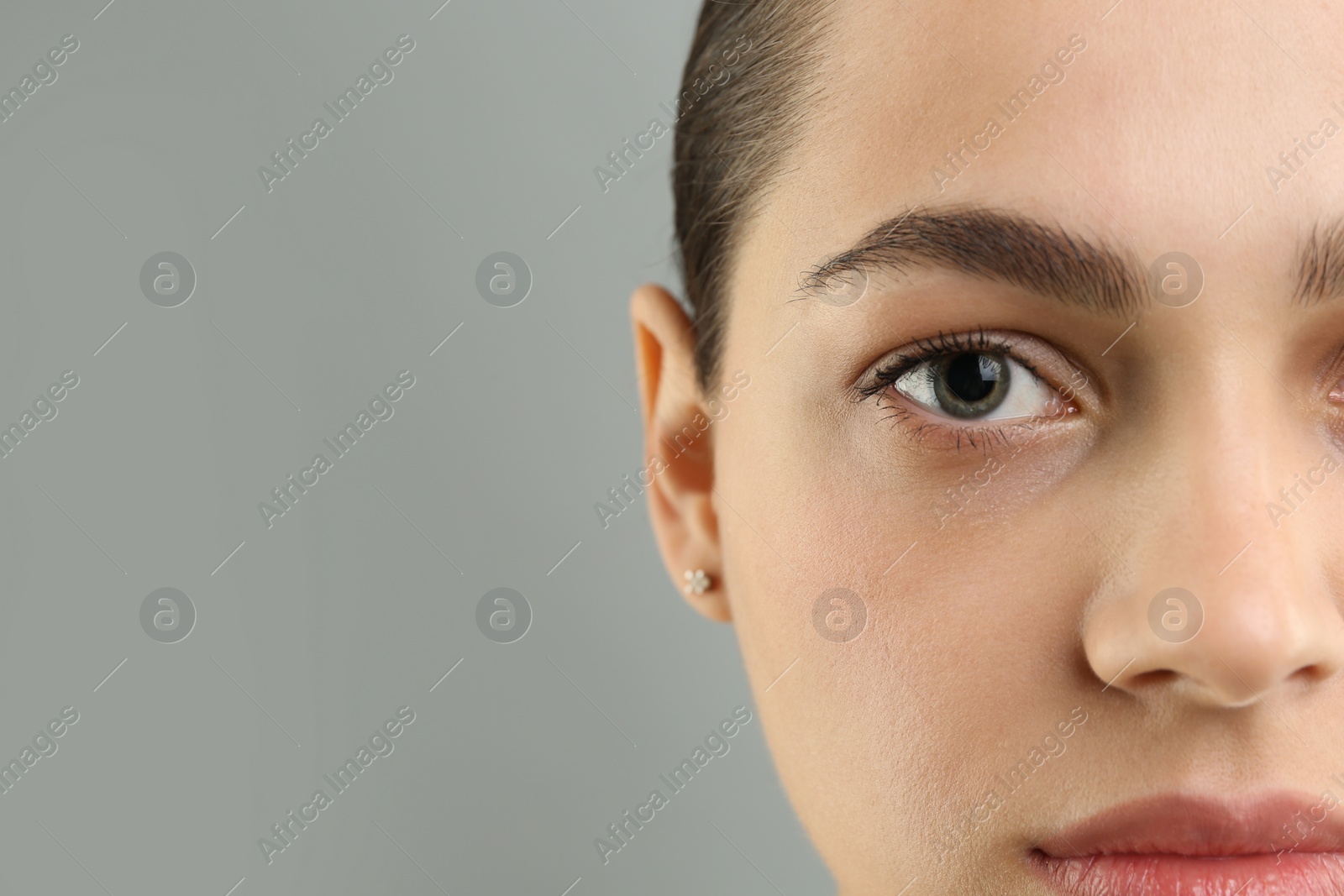 Photo of Young woman with perfect eyebrows on grey background, closeup. Space for text