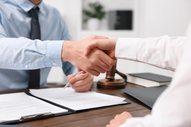 Photo of Lawyers shaking hands at wooden table in office, closeup