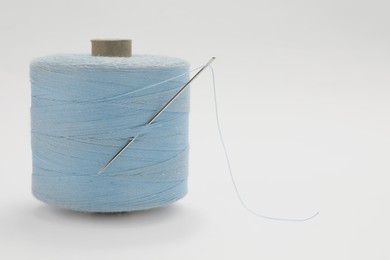 Light blue sewing thread with needle on white background