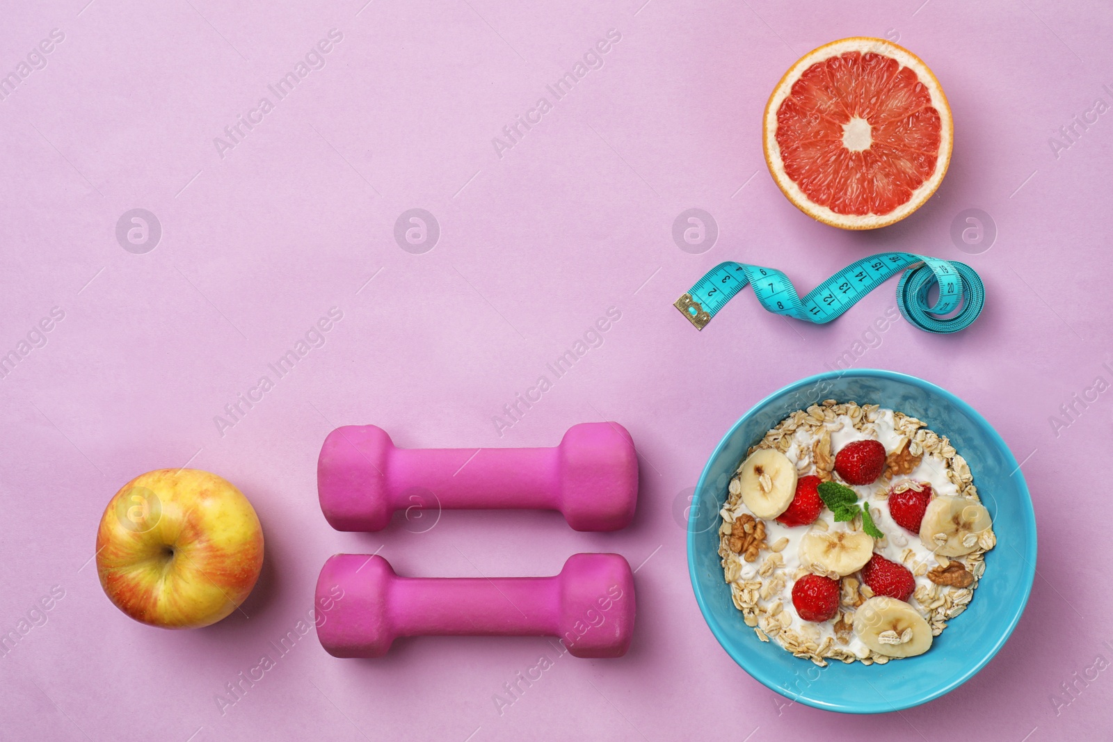 Photo of Tasty oatmeal with fresh fruits in bowl, measuring tape and dumbbells on color background, top view. Healthy diet