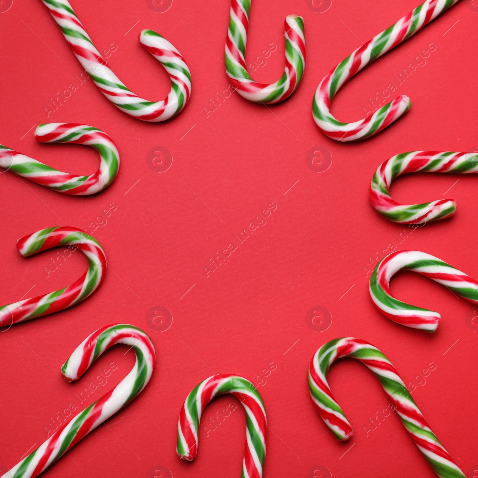 Photo of Many sweet Christmas candy canes on red background, flat lay. Space for text