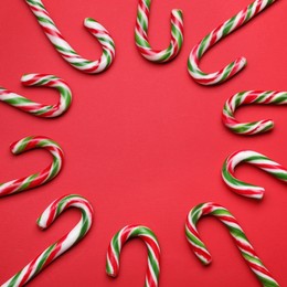 Photo of Many sweet Christmas candy canes on red background, flat lay. Space for text