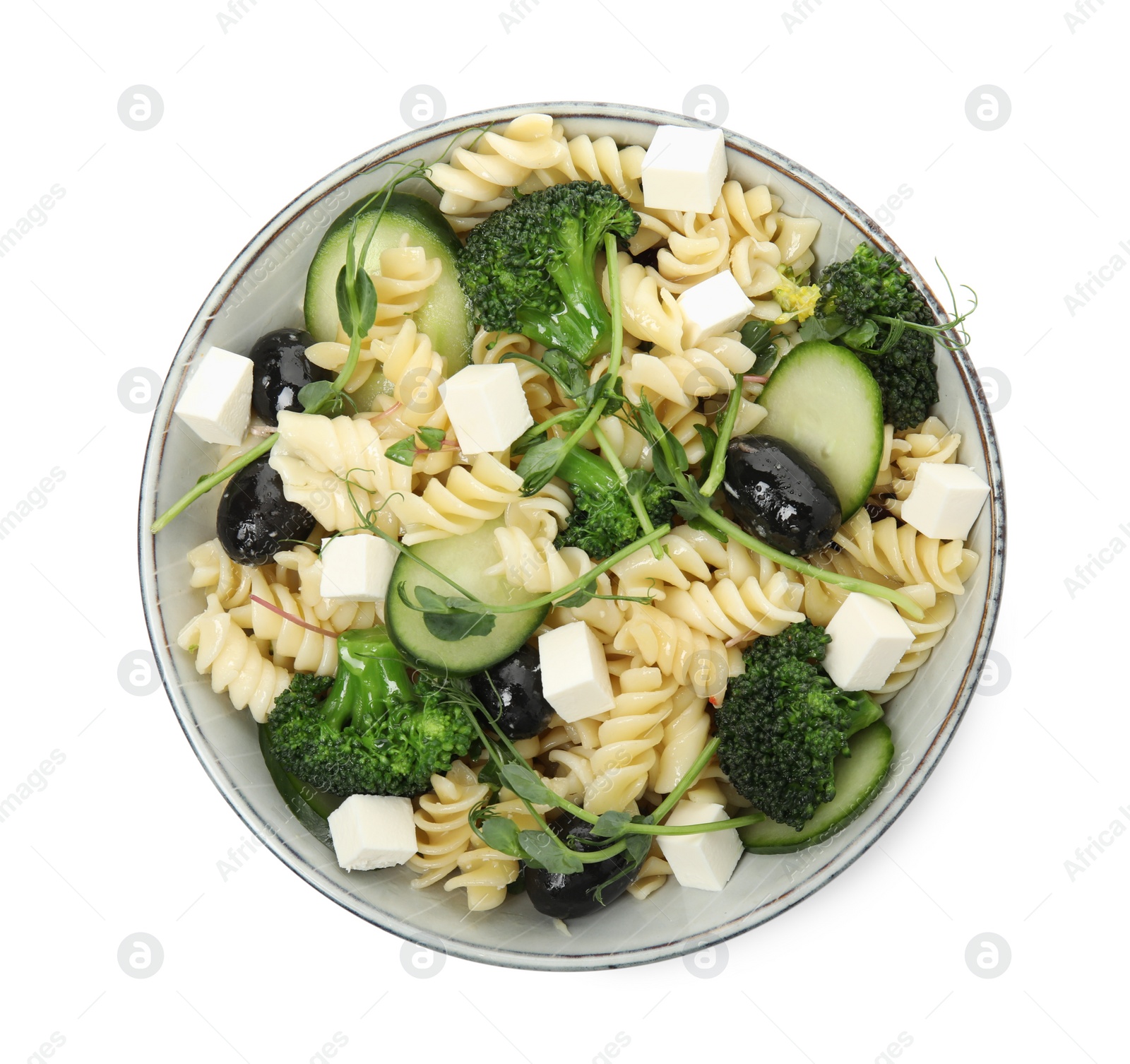 Photo of Bowl of delicious pasta with cucumber, olives, broccoli and cheese on white background, top view