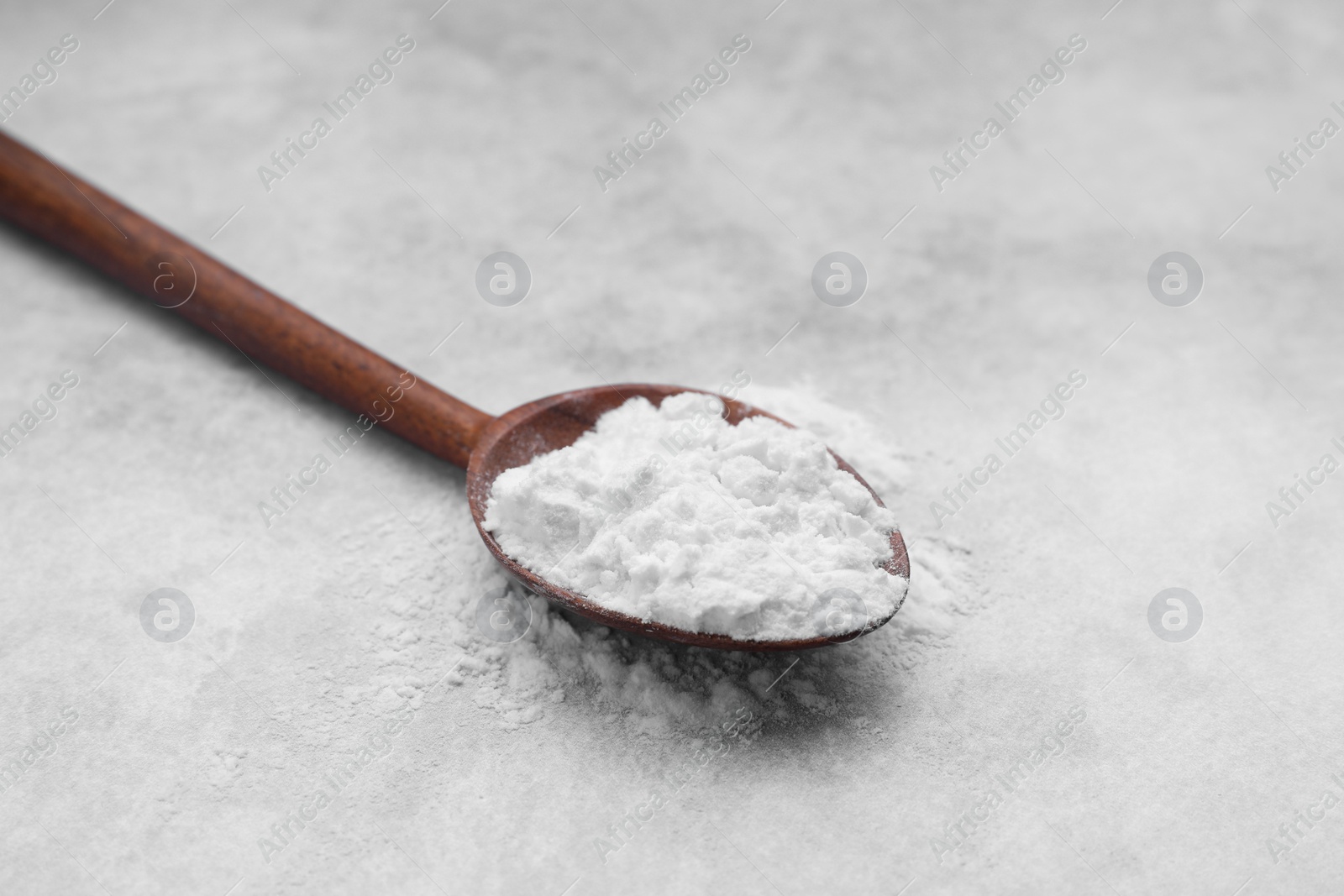 Photo of Spoon of starch on light gray table, closeup