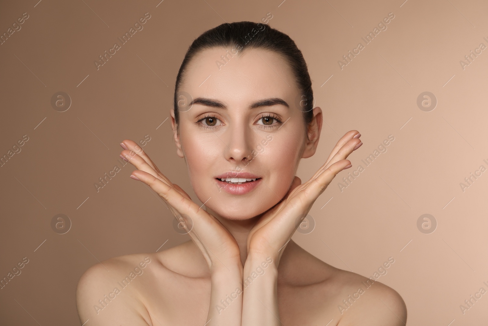 Photo of Portrait of beautiful young woman on light brown background