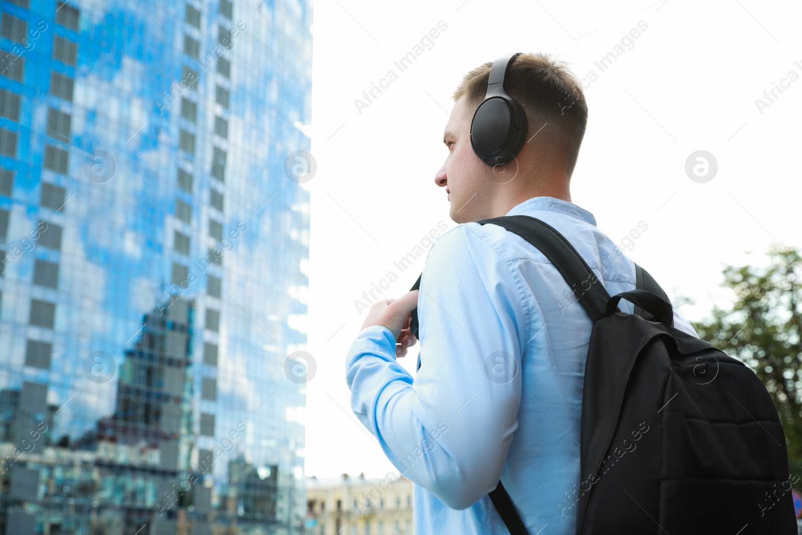 Photo of Man in headphones listening to music outdoors. Space for text