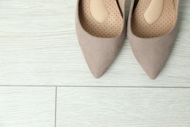 Photo of Orthopedic insoles in high heel shoes on floor, flat lay. Space for text