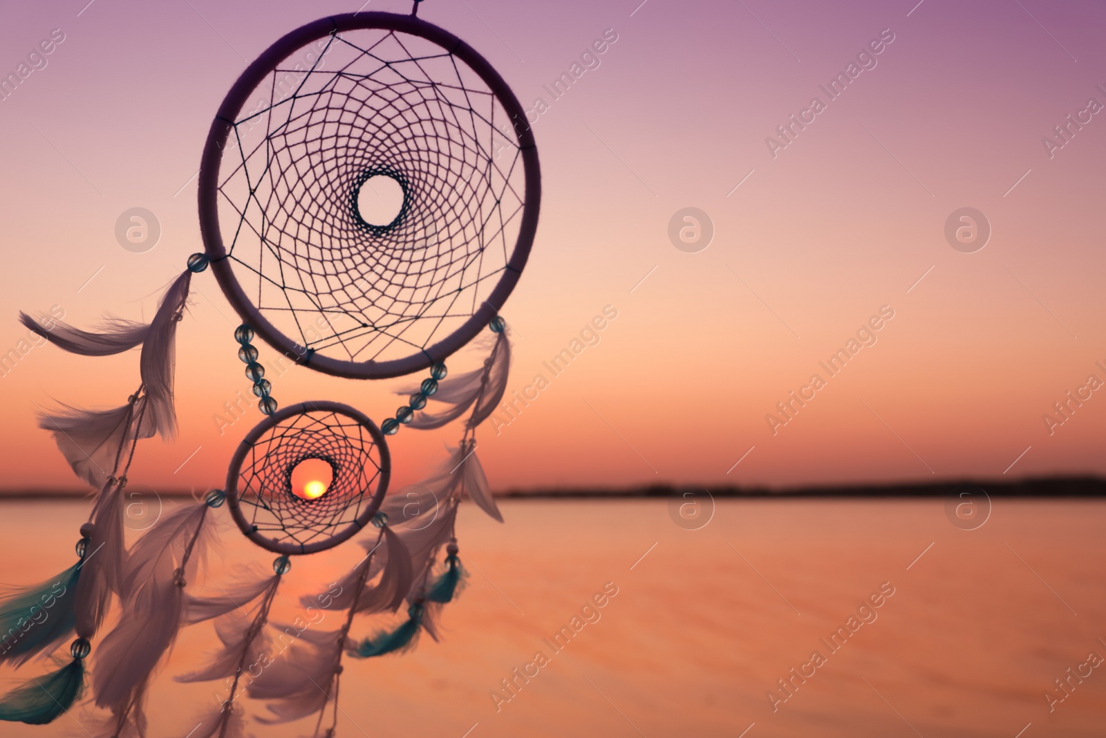 Photo of Beautiful handmade dream catcher near river at sunset. Space for text