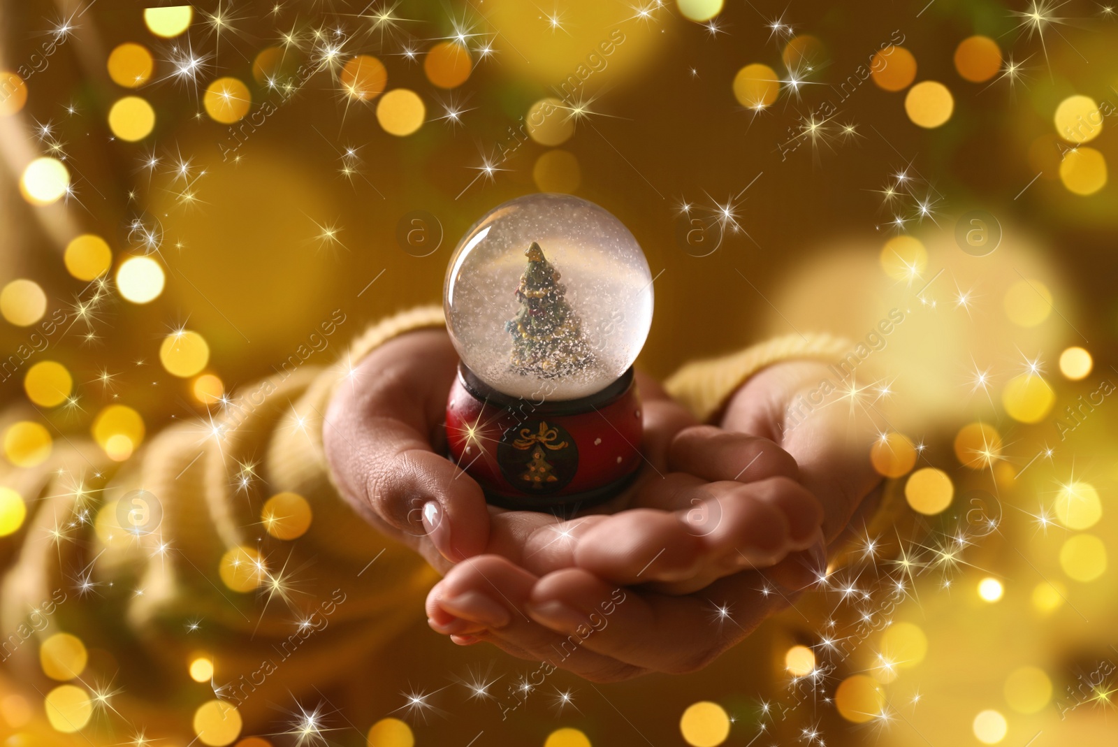 Image of Woman holding snow globe, closeup. Bokeh effect