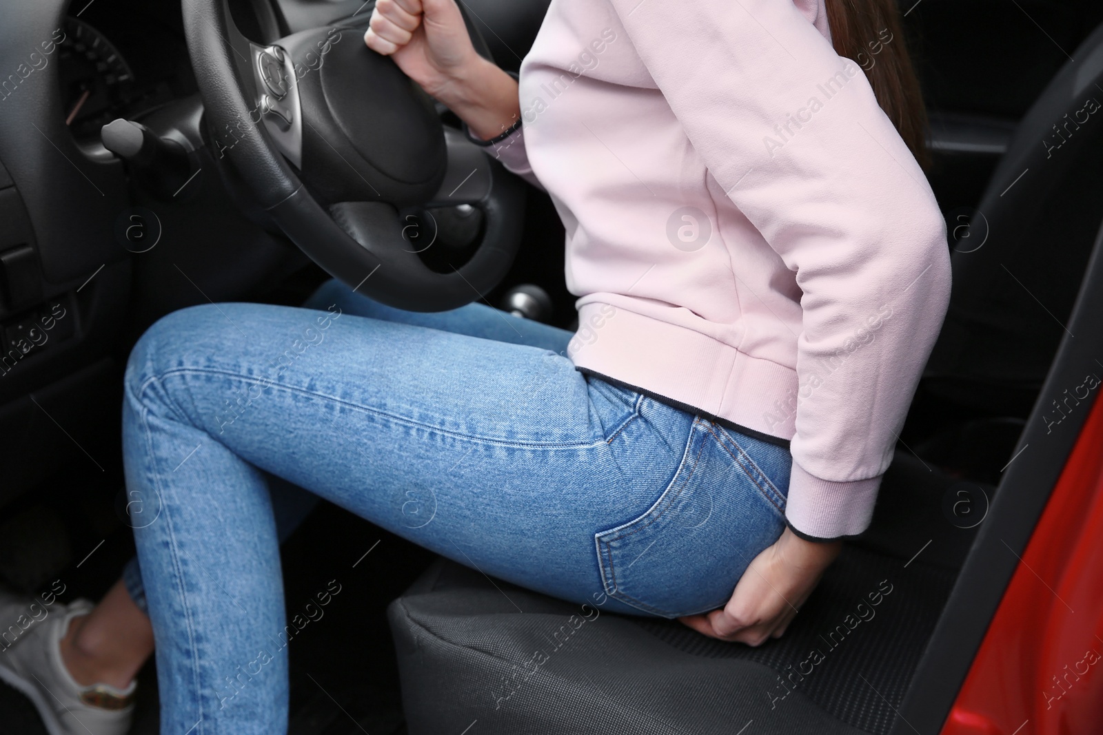 Photo of Woman suffering from hemorrhoid pain in car, closeup