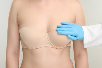 Photo of Mammologist checking woman's breast on light grey background, closeup