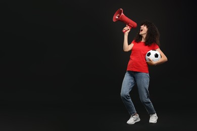 Fan with soccer ball using megaphone on black background, space for text