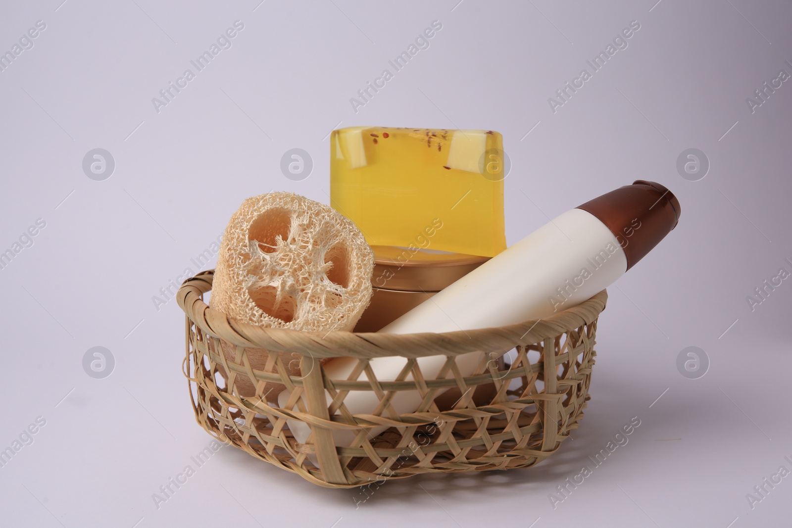Photo of Wicker basket with loofah sponge and cosmetic products on white background