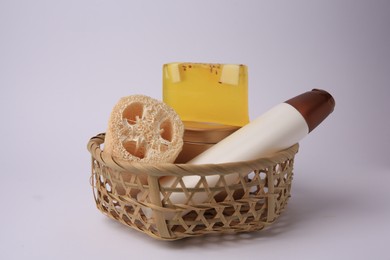 Wicker basket with loofah sponge and cosmetic products on white background