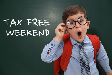 Little boy with backpack and text TAX FREE WEEKEND written on chalkboard