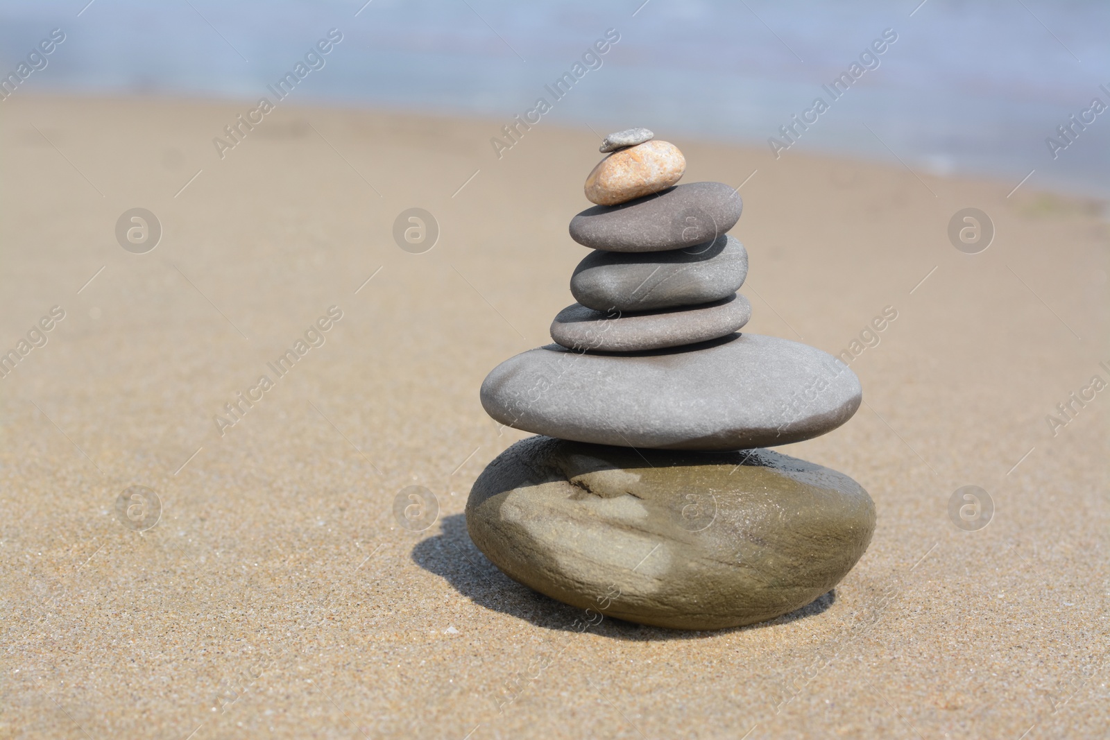 Photo of Stack of stones on sandy beach near sea, space for text