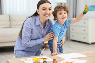 Photo of Mother and her little son painting with palms at home