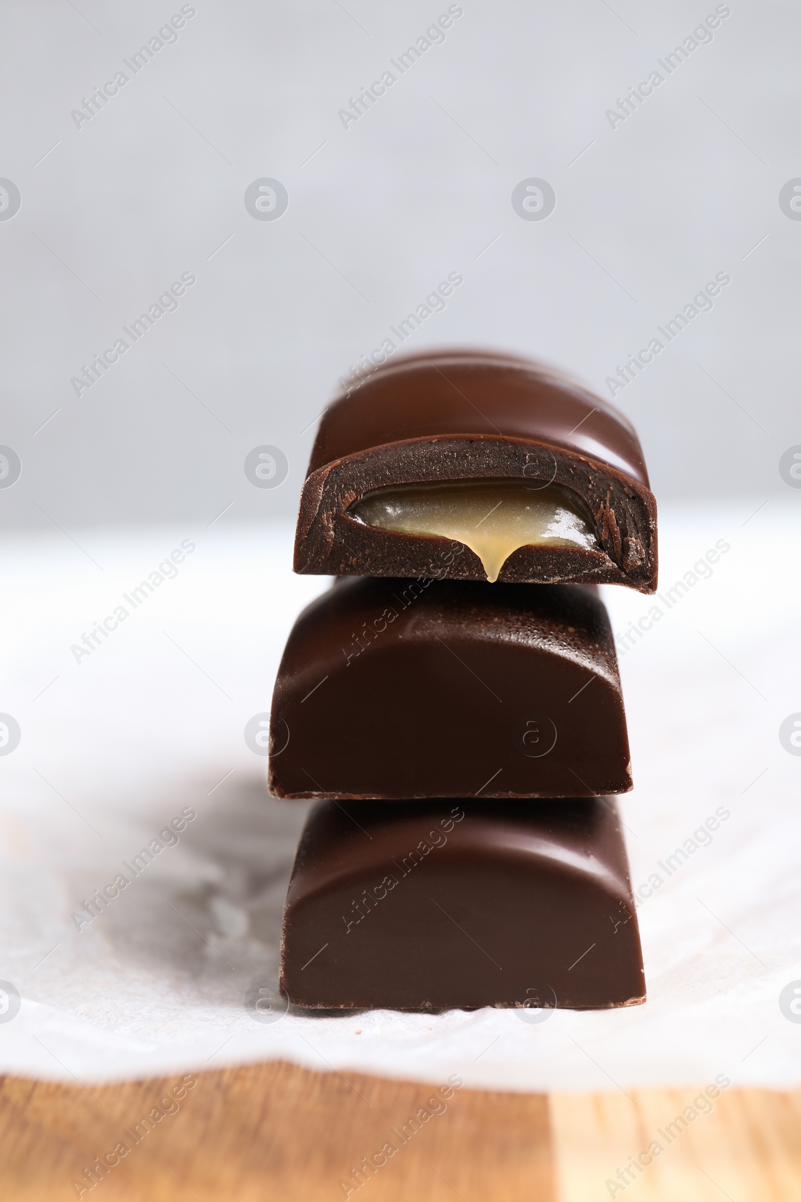 Photo of Pieces of chocolate with caramel filling on wooden table, closeup