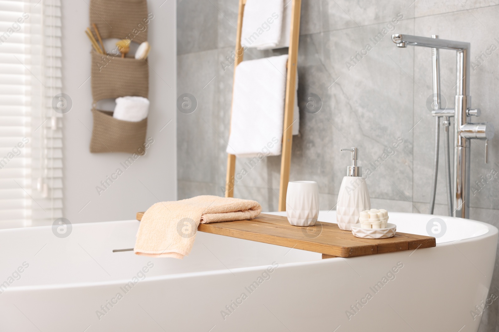 Photo of Set of different bath accessories and soap on tub in bathroom