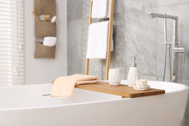 Photo of Set of different bath accessories and soap on tub in bathroom