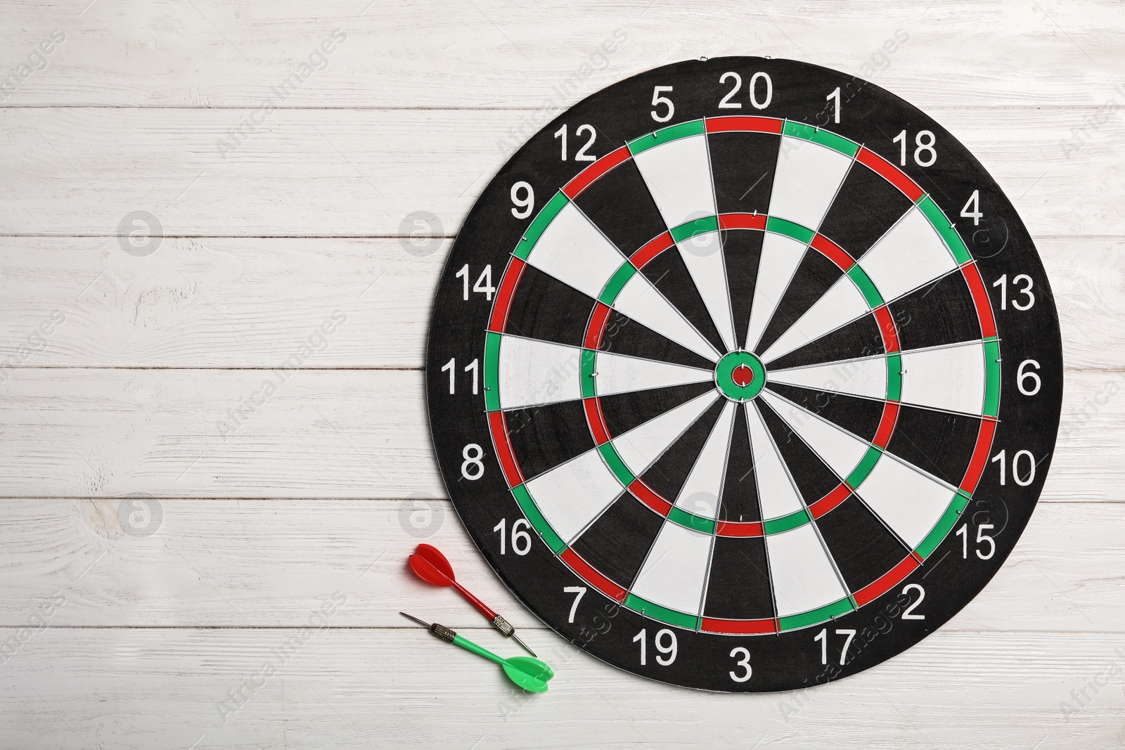 Photo of Dart board with color arrows on white wooden background, top view. Space for text