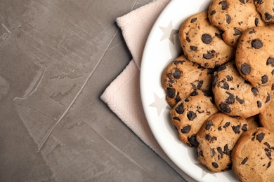 Plate with chocolate chip cookies and space for text on grey background, top view