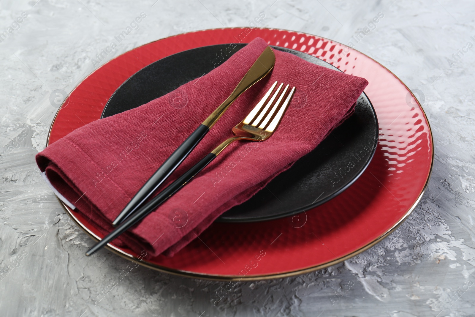 Photo of Clean plates, cutlery and napkin on gray table, closeup