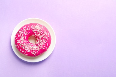 Plate with delicious doughnut on color background, top view