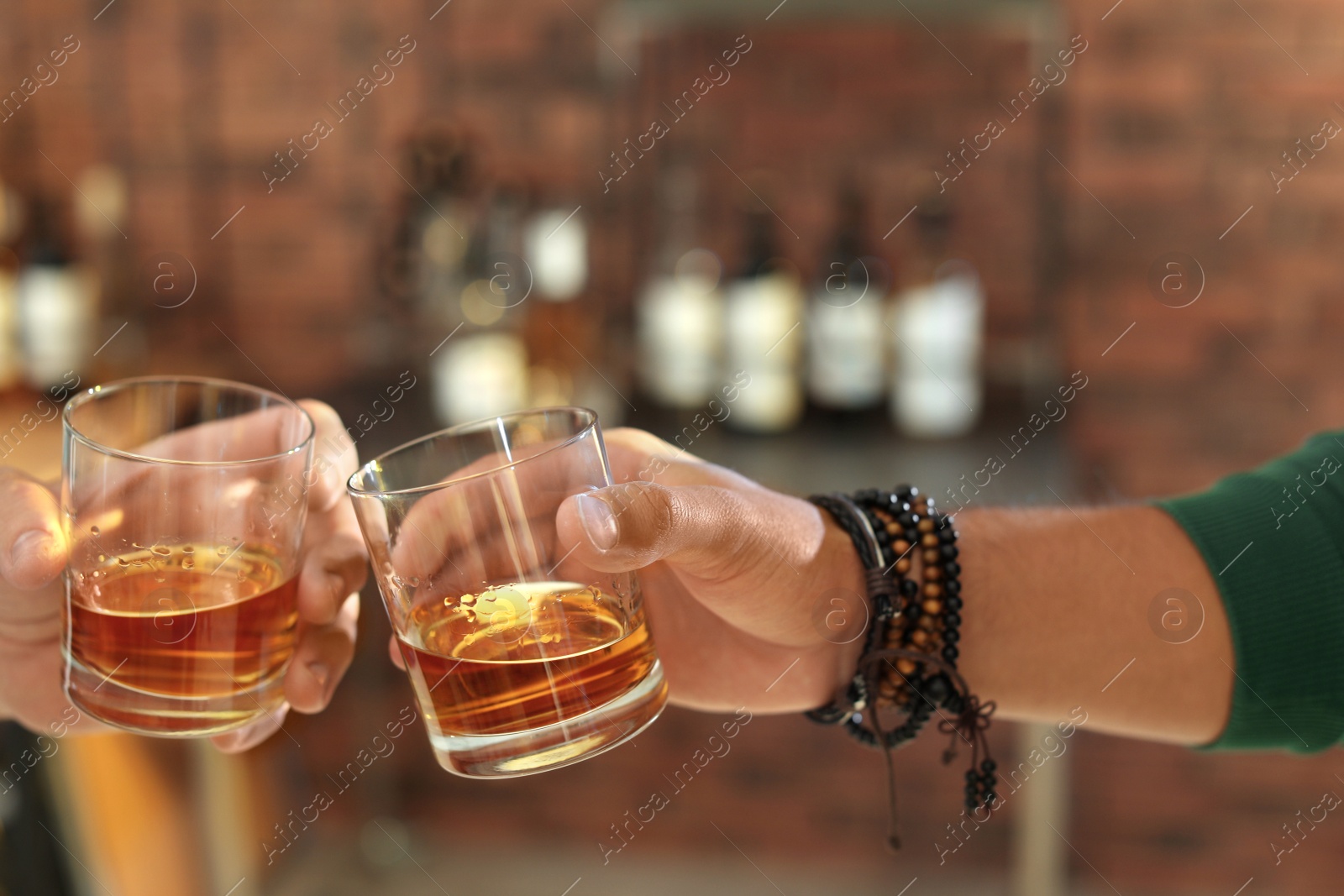 Photo of Friends toasting with glasses of whiskey indoors, closeup